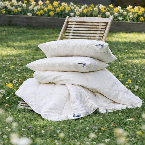 A brunette lady stretching in bed, laying under a Woolroom duvet