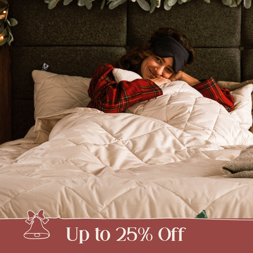 A brunette lady stretching in bed, laying under a Woolroom duvet