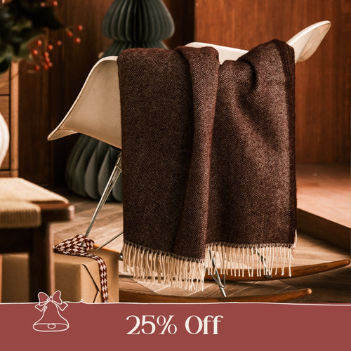 A collection of blue, green, red, beige and yellow wool throws draped over a wooden banister in a home.