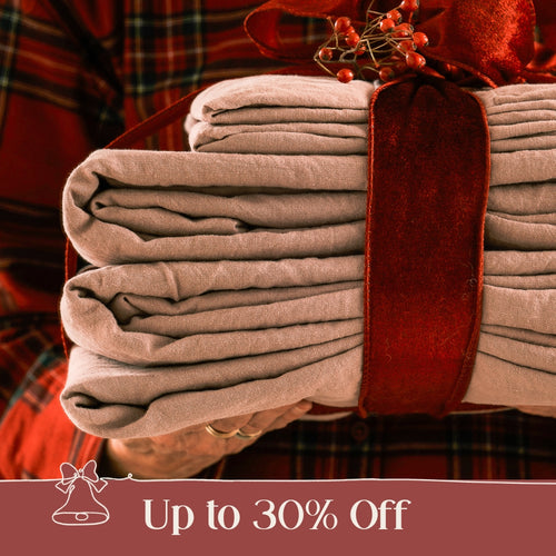 Bundle of neatly folded green bed linen, sat on a wooden bench.