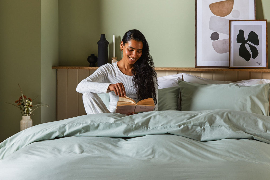 Woman reading a book on a bed in a cozy bedroom setting