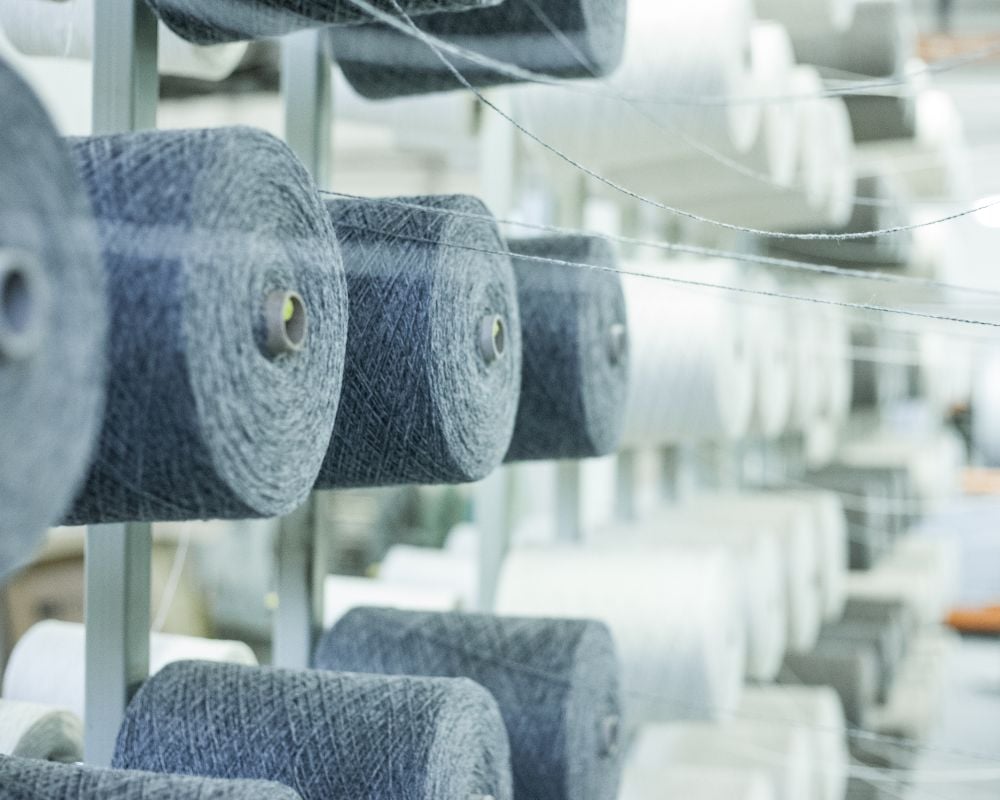Spools of fabric on a rack in a textile factory setting