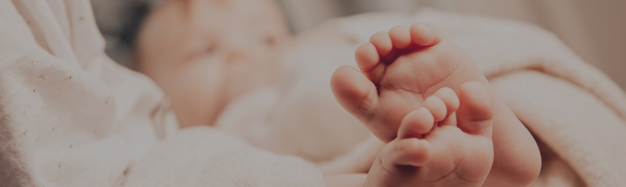 Close-up of a baby's feet held by an adult's hand, with a blurred background