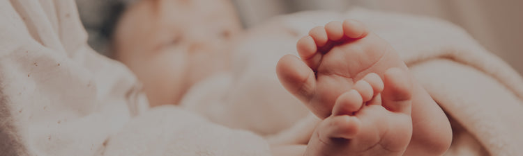 Close-up of a baby's feet held by an adult's hand, with a blurred background