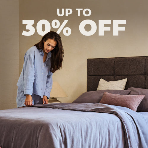 Bundle of neatly folded green bed linen, sat on a wooden bench.