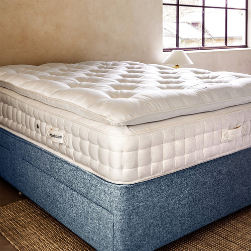 Un homme taquine la laine sur un matelas, dans l'usine Woolroom