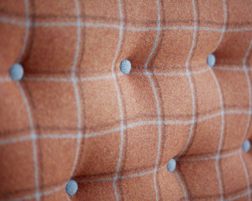 Close-up of a brown checkered fabric with tufted design and gray buttons.