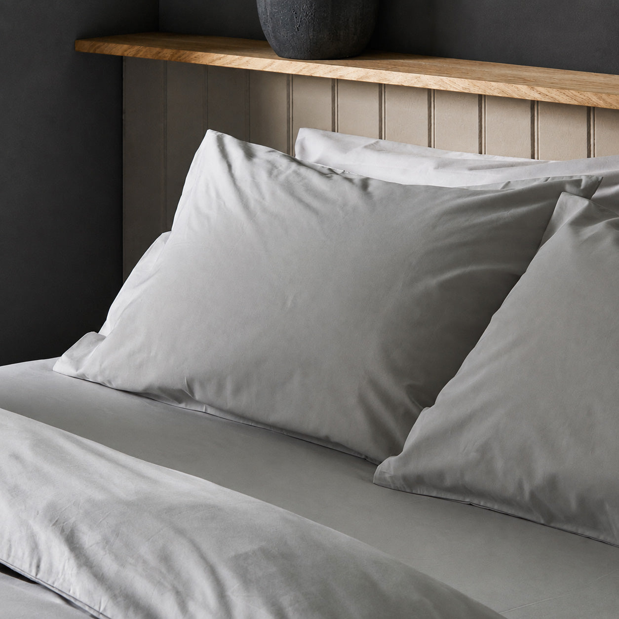 The crisp Arinta Organic Cotton Pillow Case in Earl Grey on a dressed bed with four pillows.