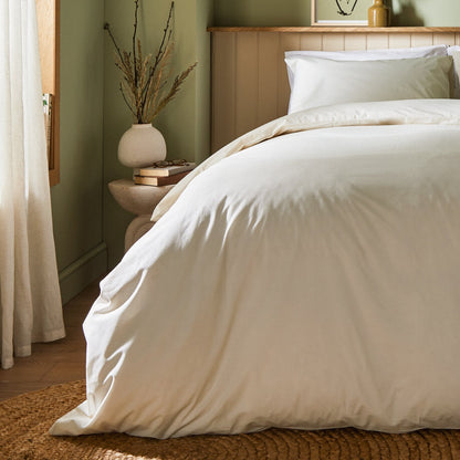 A dressed bed with Arinta Organic Cotton Comforter Cover in Vanilla has the comforter turned down and two pillows.