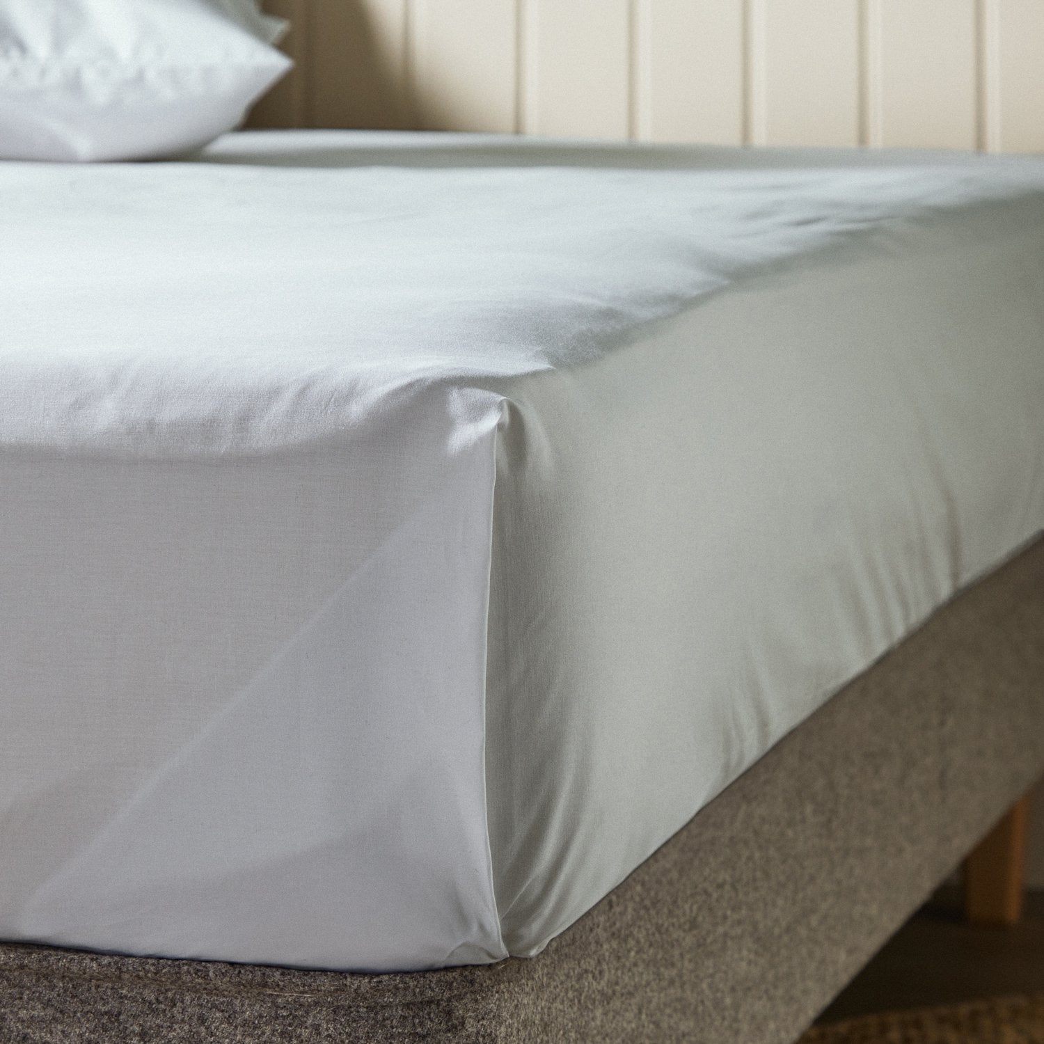 Woolroom's Arinta Organic Cotton top sheet in Earl Grey draped over the end of a bed.