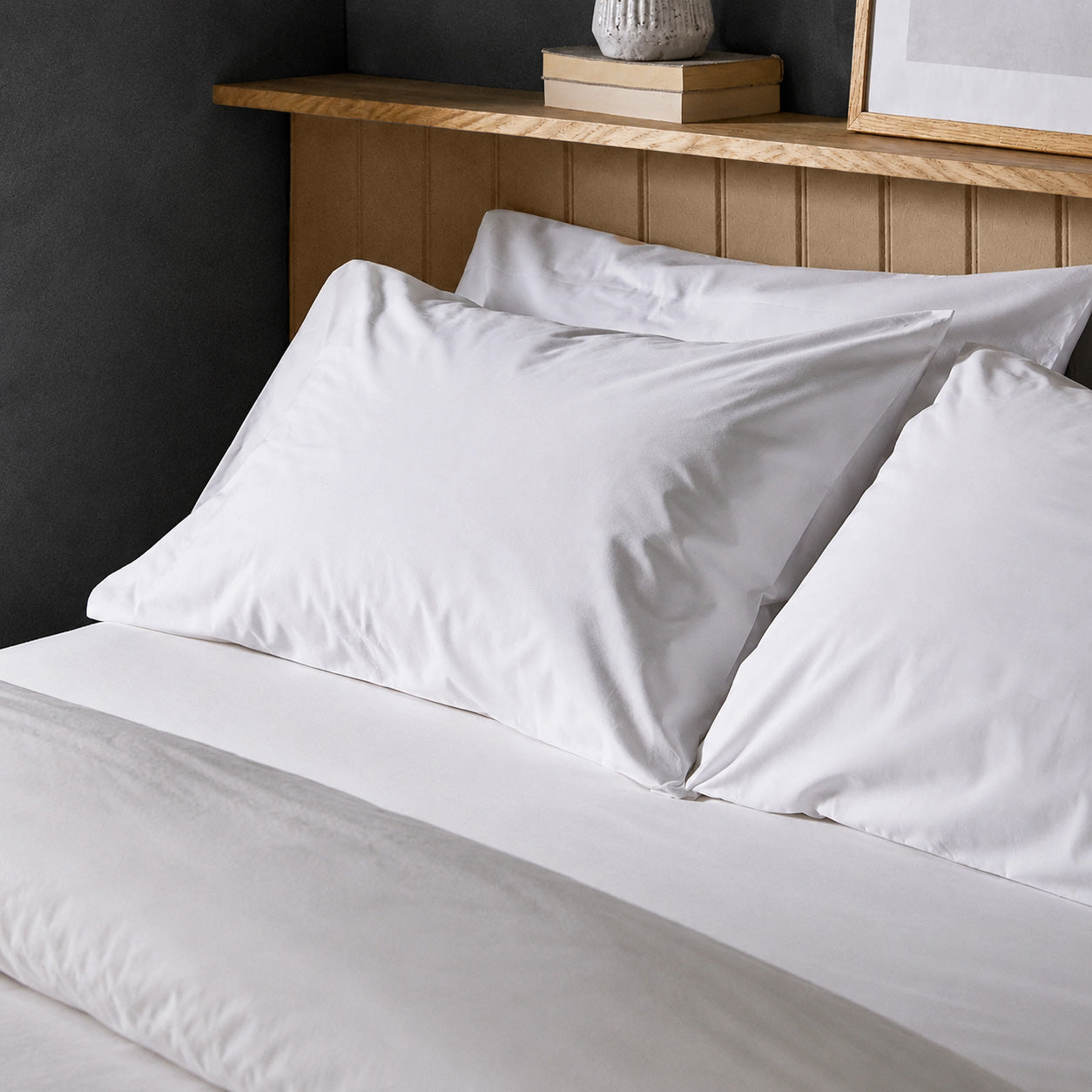 The crisp Arinta Organic Cotton Pillow Case in White on a dressed bed with four pillows.