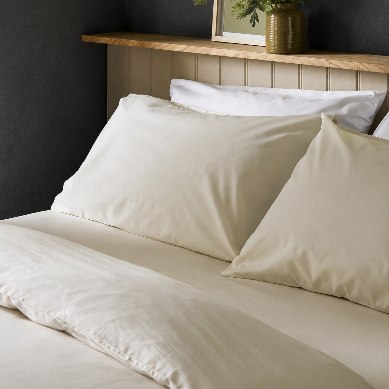 The crisp Arinta Organic Cotton Pillow Case in Vanilla on a dressed bed with four pillows.