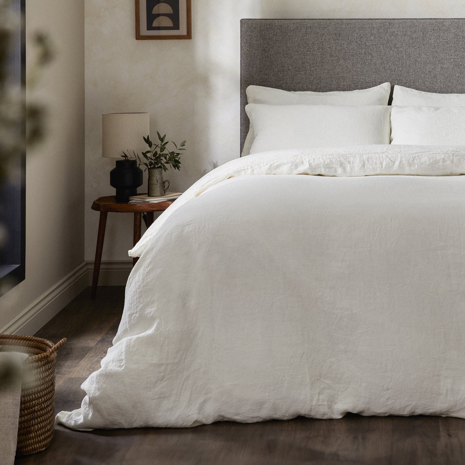 A dressed bed with Woolroom's Mariana Linen Comforter Cover in Ivory has the comforter turned down and two pillows. 