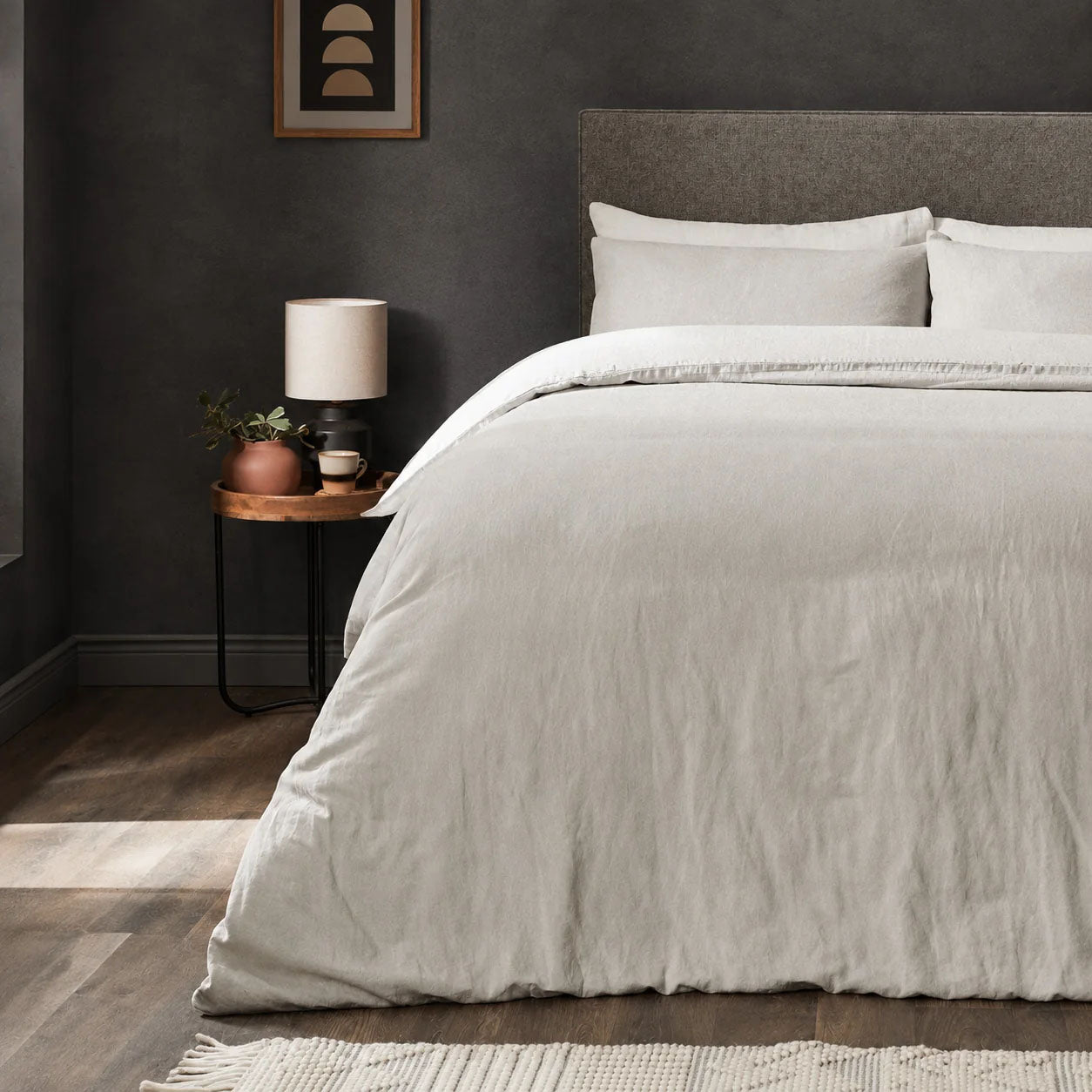 A dressed bed with Woolroom's Mariana Linen Comforter Cover in Pebble has the comforter turned down and two pillows. 