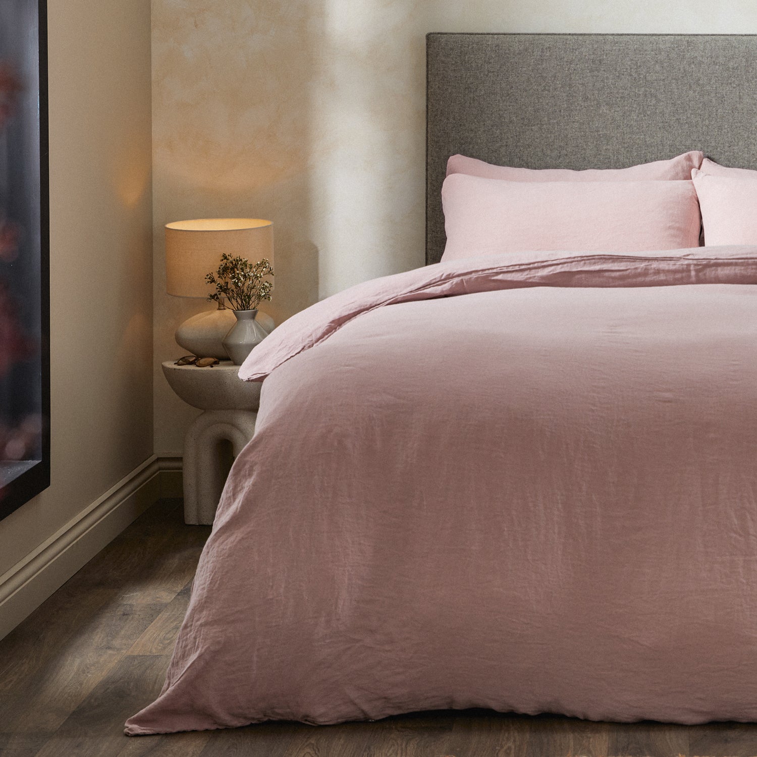 A dressed bed with Woolroom's Mariana Linen Comforter Cover in Rose has the comforter turned down and two pillows. 