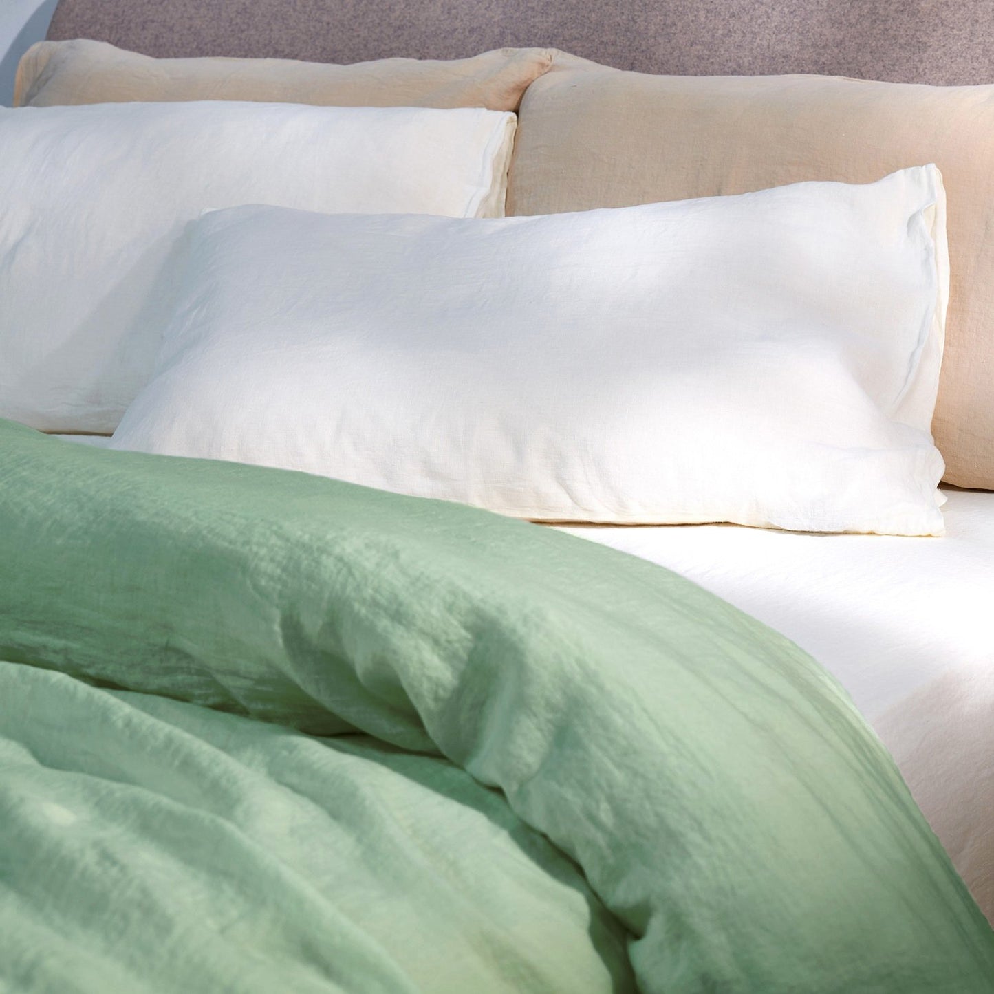 A dressed bed using the Mariana Mix & Match Linen Set Builder with sage comforter cover, ivory sheets, and sand pillow cases.