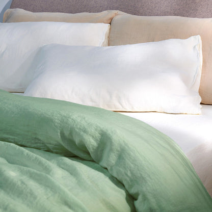 A dressed bed using the Mariana Mix & Match Linen Set Builder with sage comforter cover, ivory sheets, and sand pillow cases.