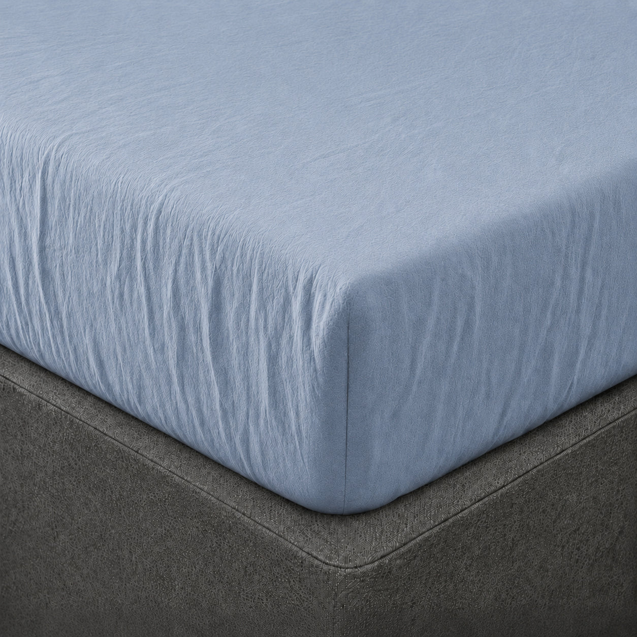 A close up of the corner of a mattress with Woolroom's Mariana Linen Blend Fitted Sheet in Cornflower.