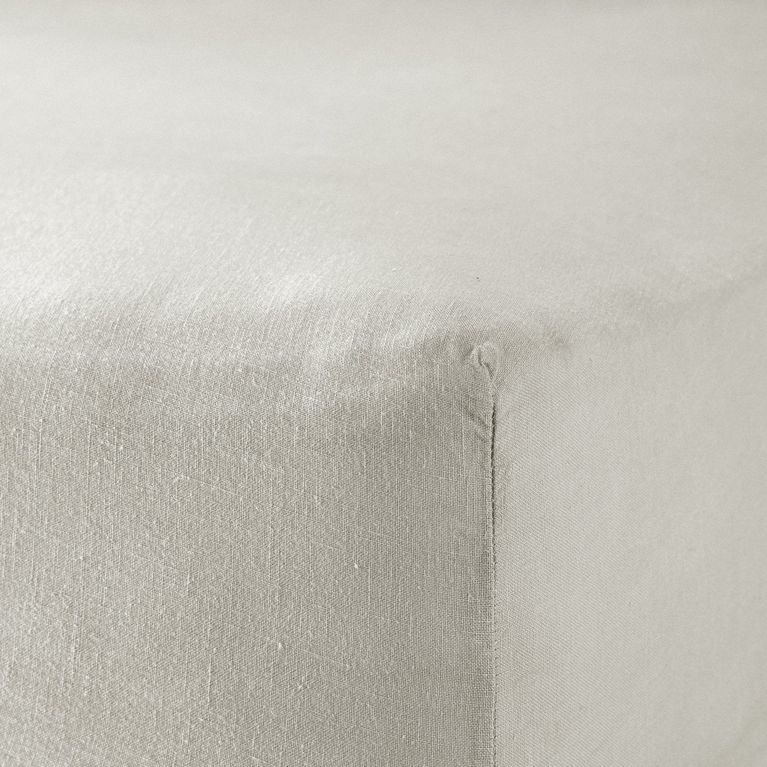 A close up of the corner of a mattress with Woolroom's Mariana Linen Blend Fitted Sheet in Pebble.