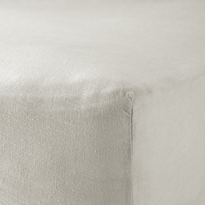 A close up of the corner of a mattress with Woolroom's Mariana Linen Blend Fitted Sheet in Pebble.