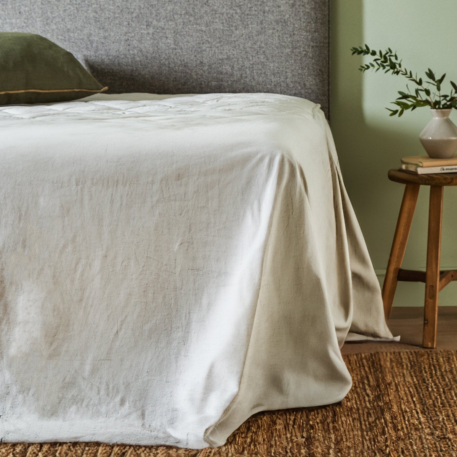 Woolroom's Mariana Linen Blend top sheet in Ivory draped over the end of a bed.