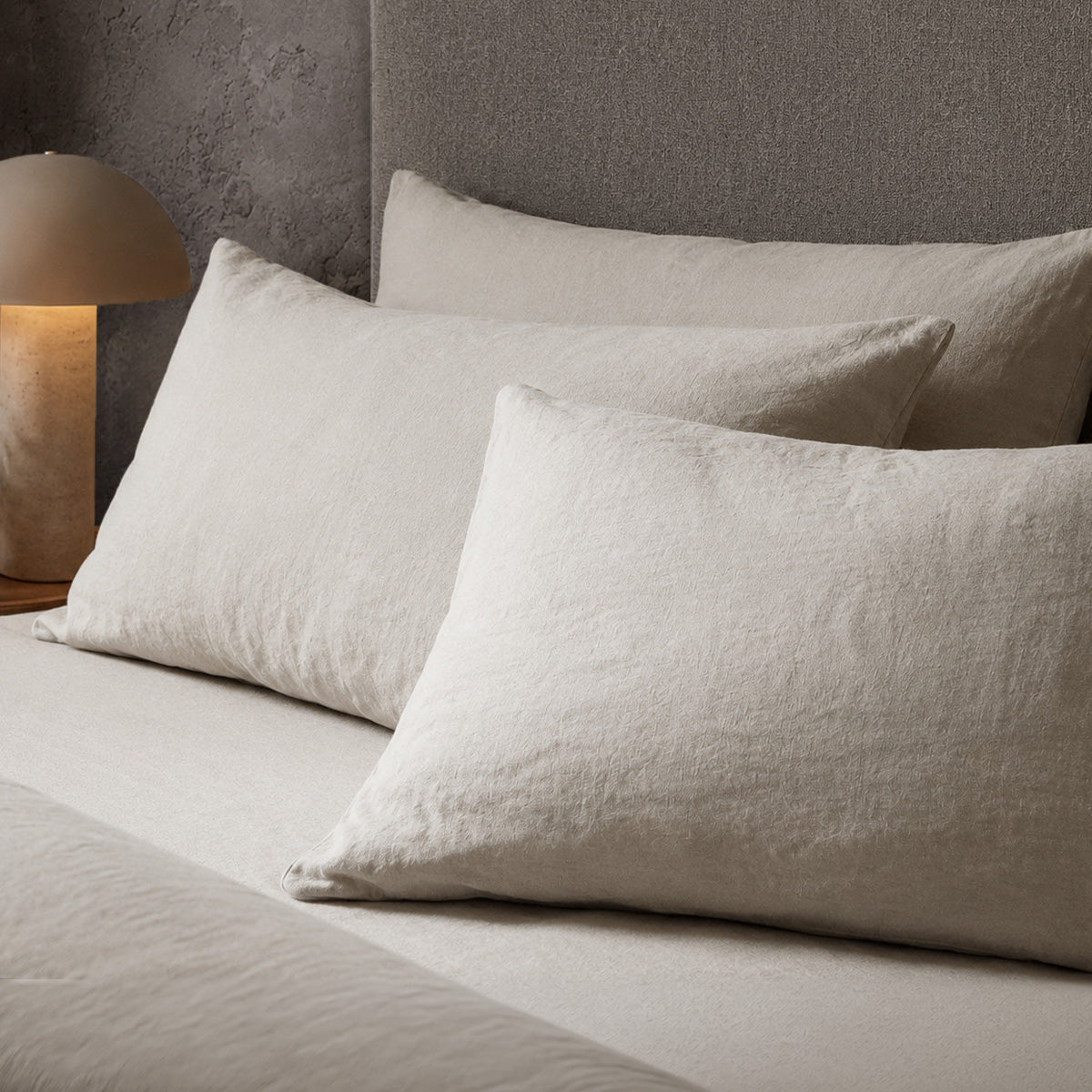 Four pillows on a dressed bed with the Mariana Linen Blend Pillow Cases in Pebble.