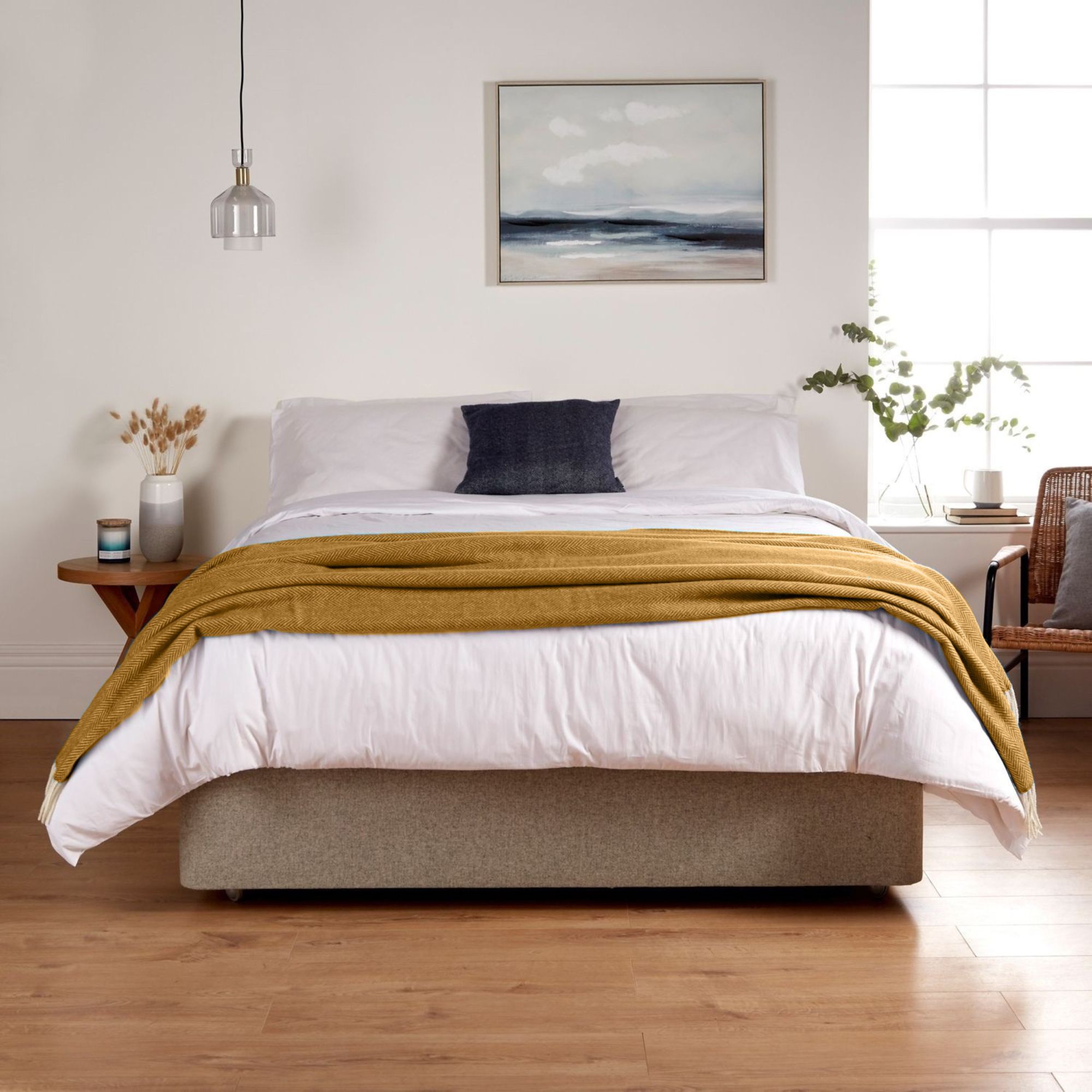A bedroom showing the Woolroom Chianti Wide Throw in color Tuscany Gold draped across the foot of the bed.