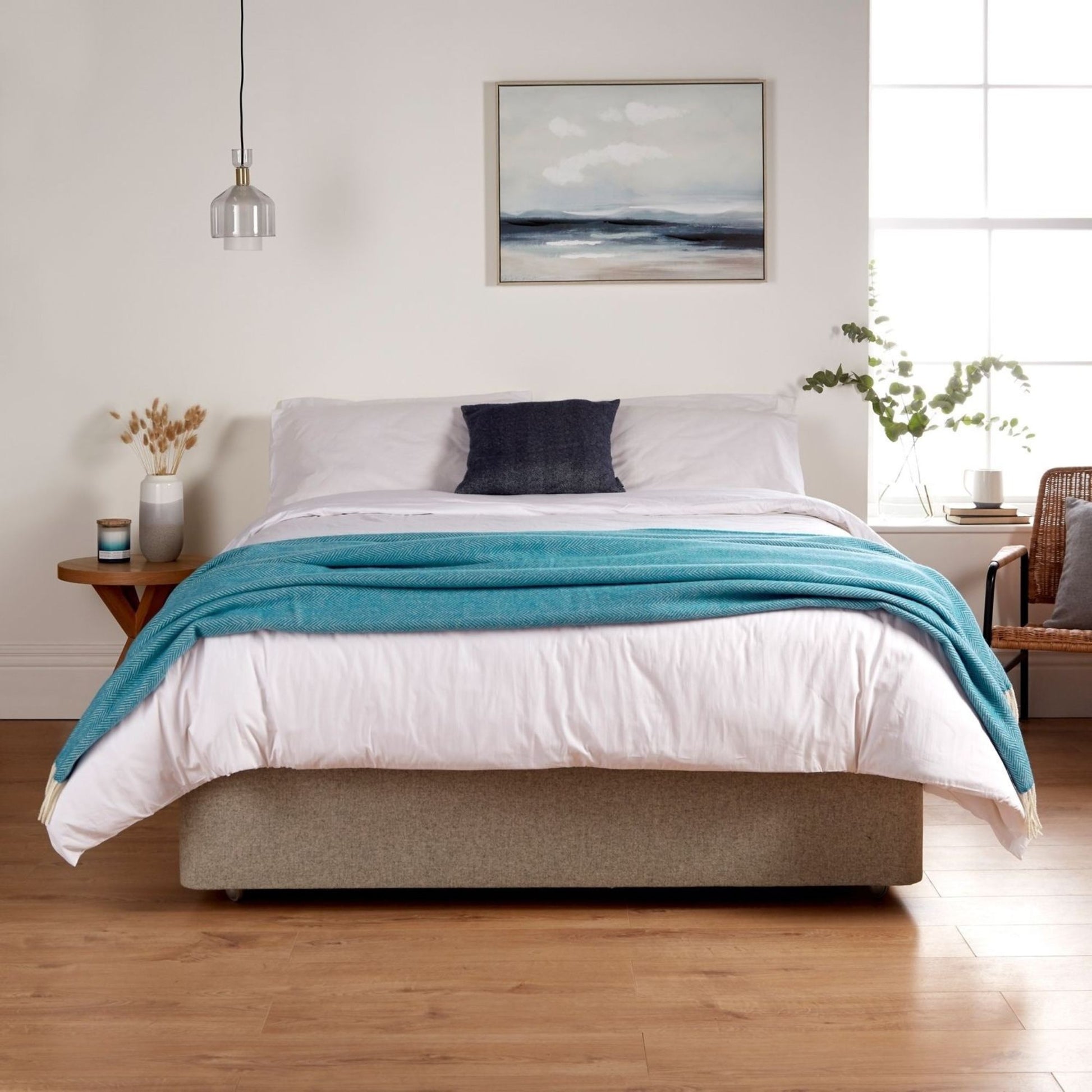 A bedroom showing the Woolroom Chianti Wide Throw in color Caribbean Blue draped across the foot of the bed.