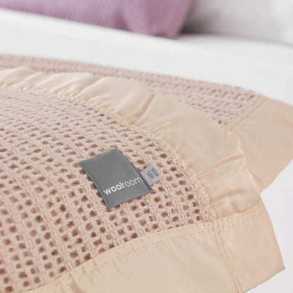 The Woolroom Ribblesdale Cellular Wool Bed Blanket in the color Mocha has a breathable open weave texture with a satin edge.