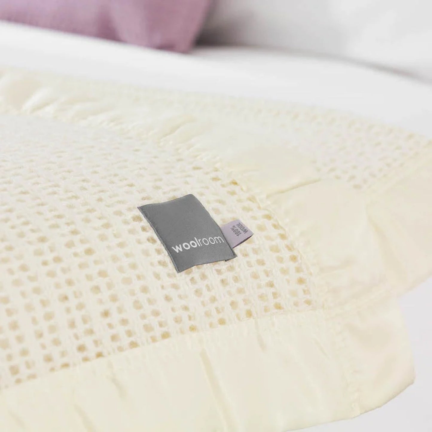The Woolroom Ribblesdale Cellular Wool Bed Blanket in the color Pearl has a breathable open weave texture with a satin edge.