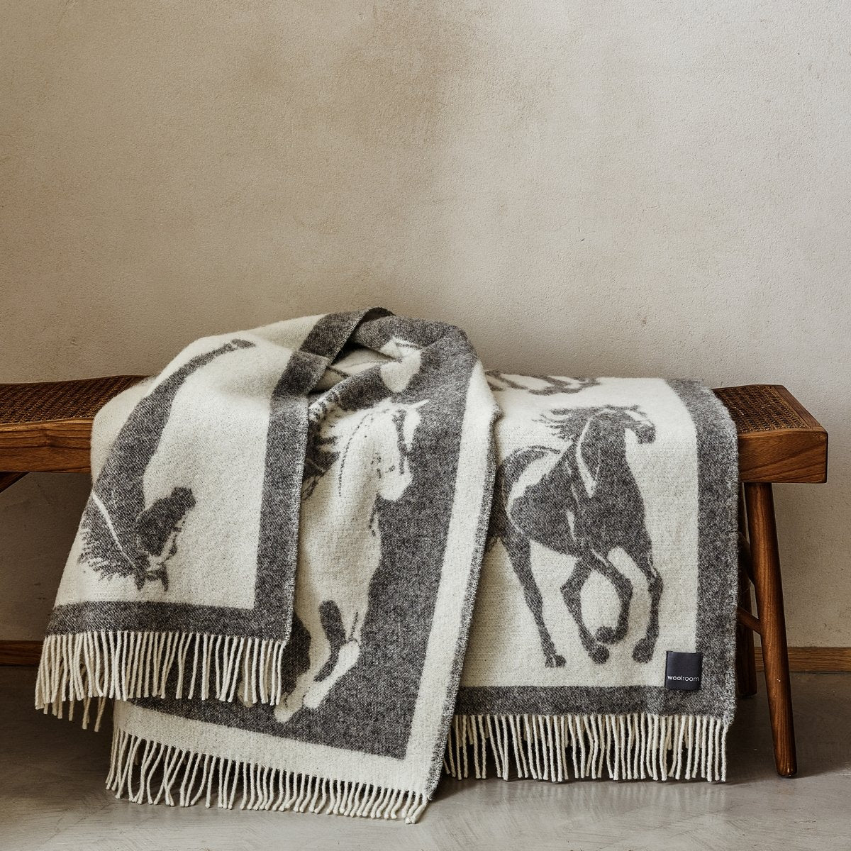 The playful Wild and Wool Horse Wool Throw in Stone with white fringe belongs to the Woolroom animal throw collection.