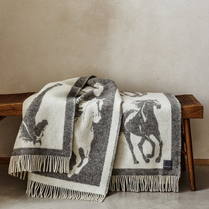 The playful Wild and Wool Horse Wool Throw in Stone with white fringe belongs to the Woolroom animal throw collection.