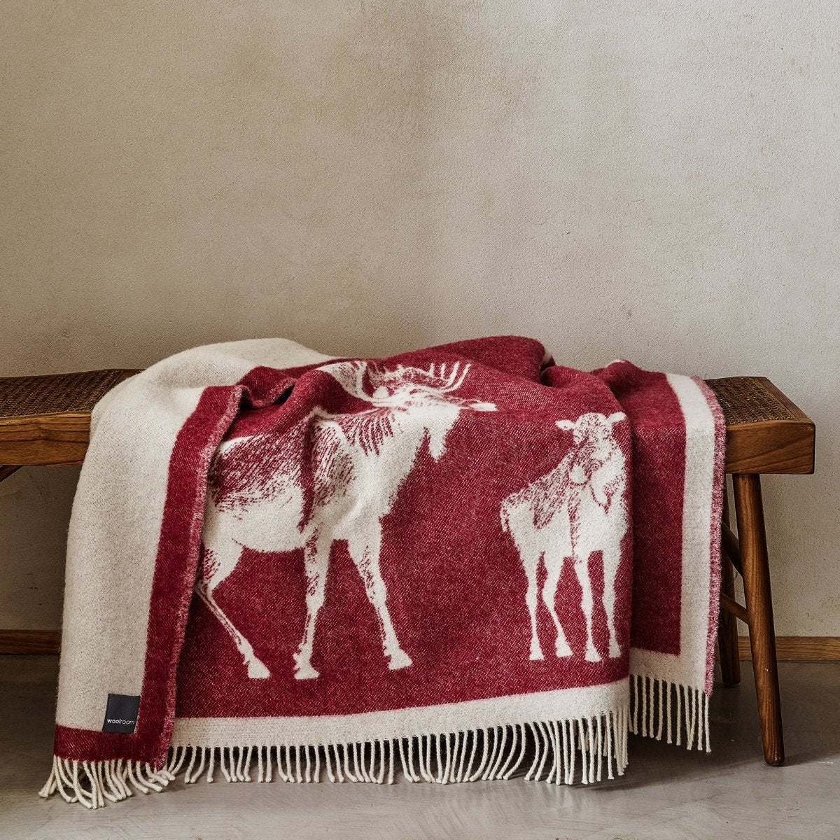 The playful Wild and Wool Moose Wool Throw in Berry with white fringe belongs to the Woolroom animal throw collection.