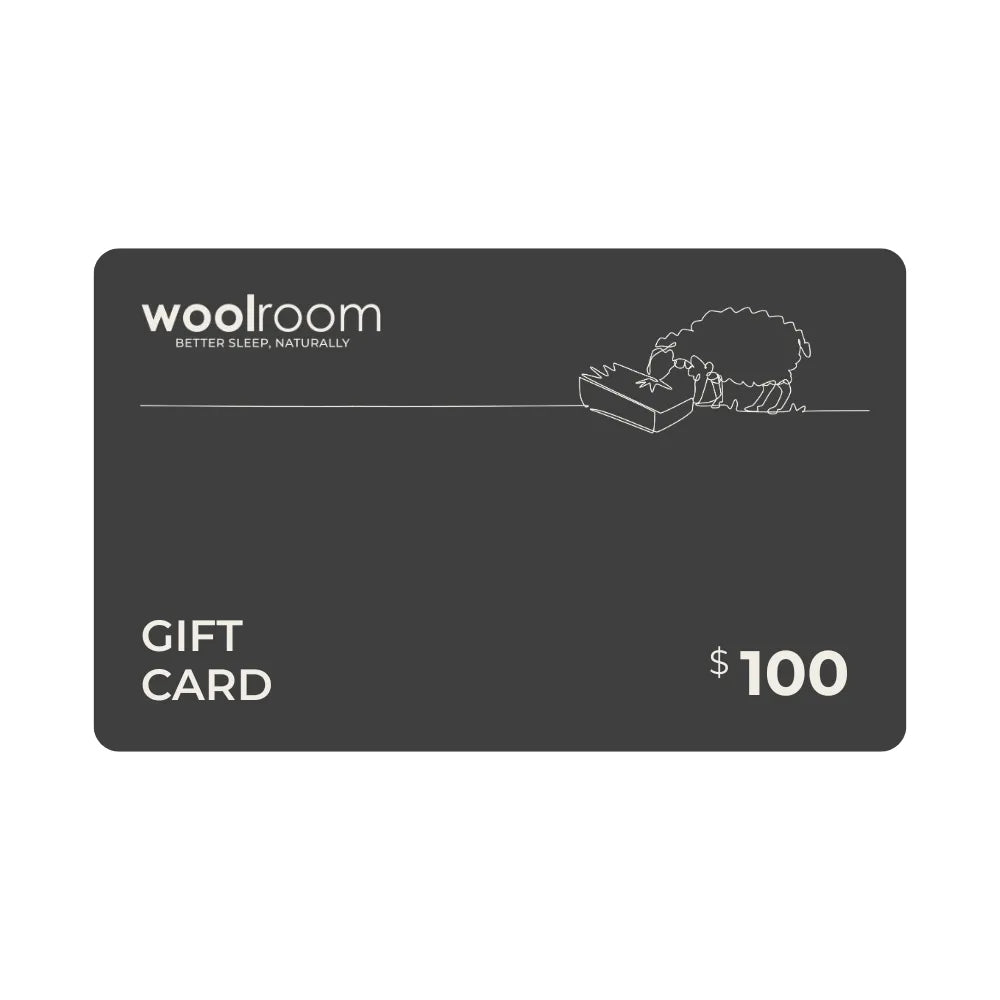 A dark gray Woolroom gift card with white text reading 'woolroom' and 'GIFT CARD', plus a small line drawing of a sheep and the amount '$100' on a plain white background.