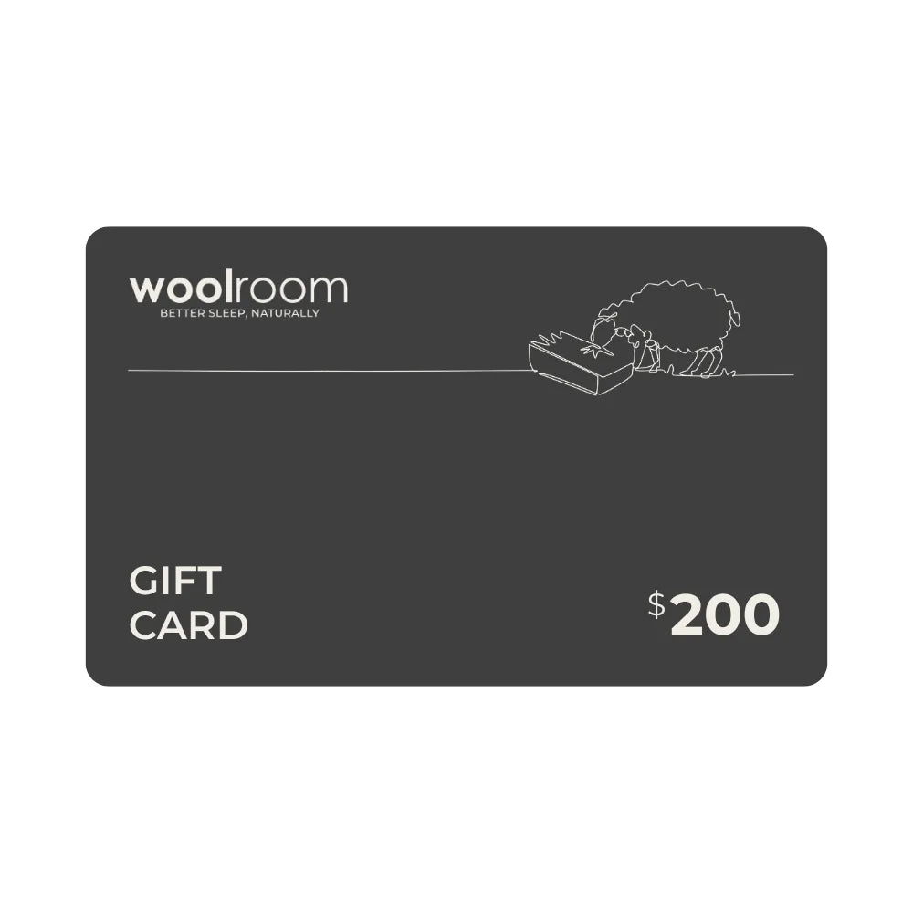 A dark gray Woolroom gift card with white text reading 'woolroom', 'GIFT CARD', and '$200', plus a small white line drawing of a sheep on a box. The card is centered on a plain white background.