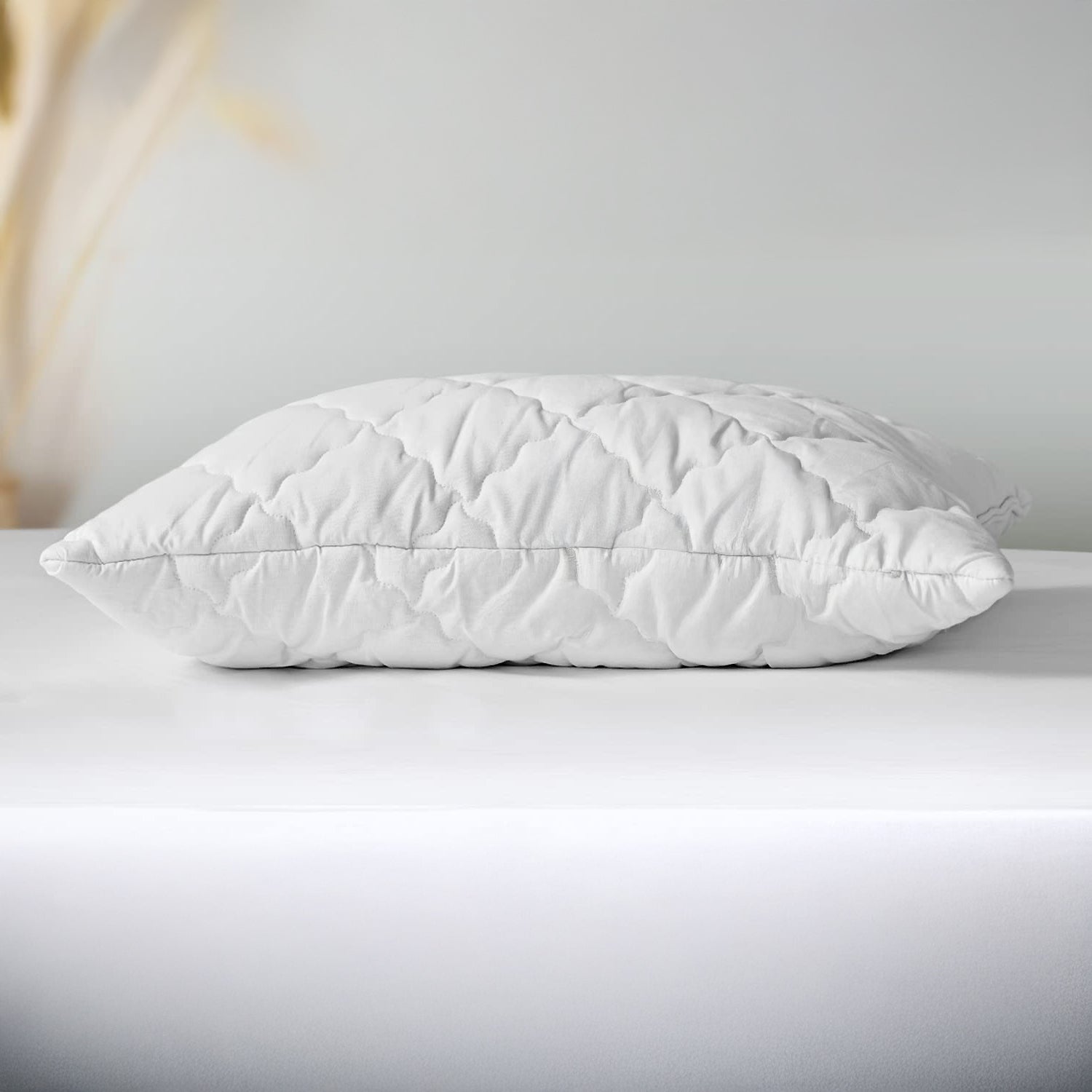 White quilted pillow on a light gray surface with a neutral background